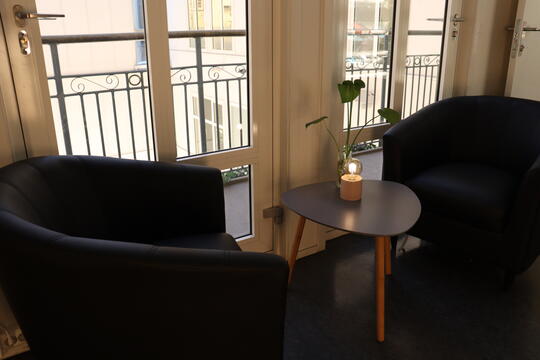 Bilde av to stoler og et bord ved inngangen i Stua. De står inntil et stort vindu.