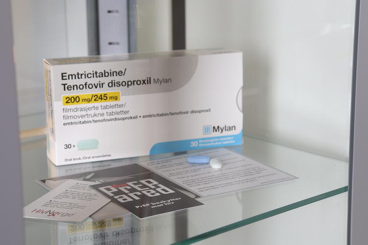 Et bilde av en pakke PREP og informasjonsmateriell som ligger til utstilling i et glasskap på Pro Sentret. Foran pakken ligger to piller. Et bilde av en pakke PREP og informasjonsmateriell som ligger til utstilling i et glasskap på Pro Sentret. Foran pakken ligger to piller.