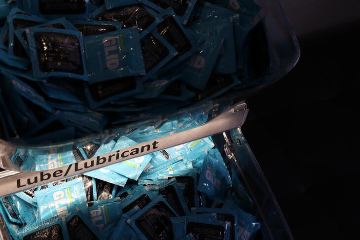 Et nærbilde av en skuff i kondomstativet. Den er fylt med små, blå pakker med glidemiddel. Et nærbilde av en skuff i kondomstativet. Den er fylt med små, blå pakker med glidemiddel.